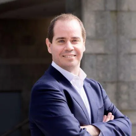man wearing suit jacket smiling into camera